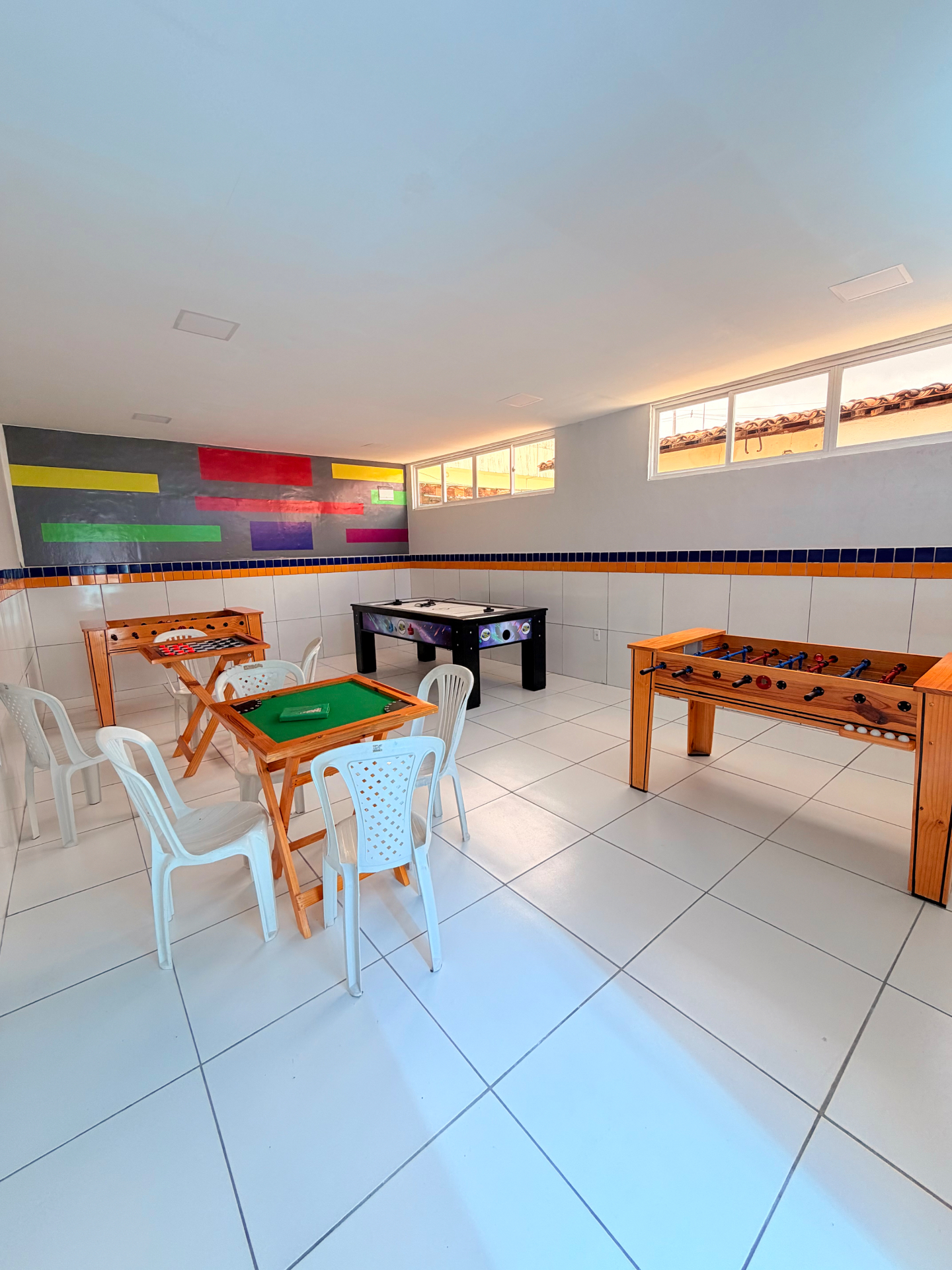 Sala de jogos com mesas de pebolim, sinuca e jogos de mesa
